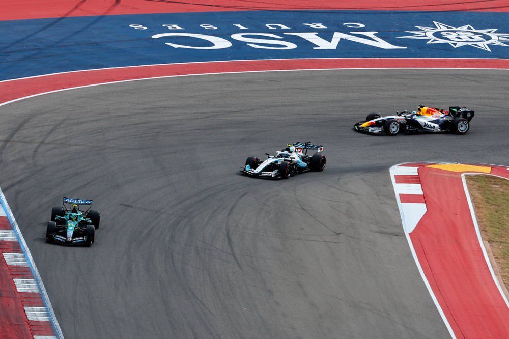 Aston Martin F1 car of Fernando Alonso leads a Williams and an Albon-style Williams-era rival through a COTA turn; Formula 1 race action Shorter, accurate ve…