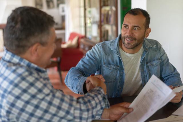 Two Latin American farmers closing a deal with a handshake at a farm - business concepts