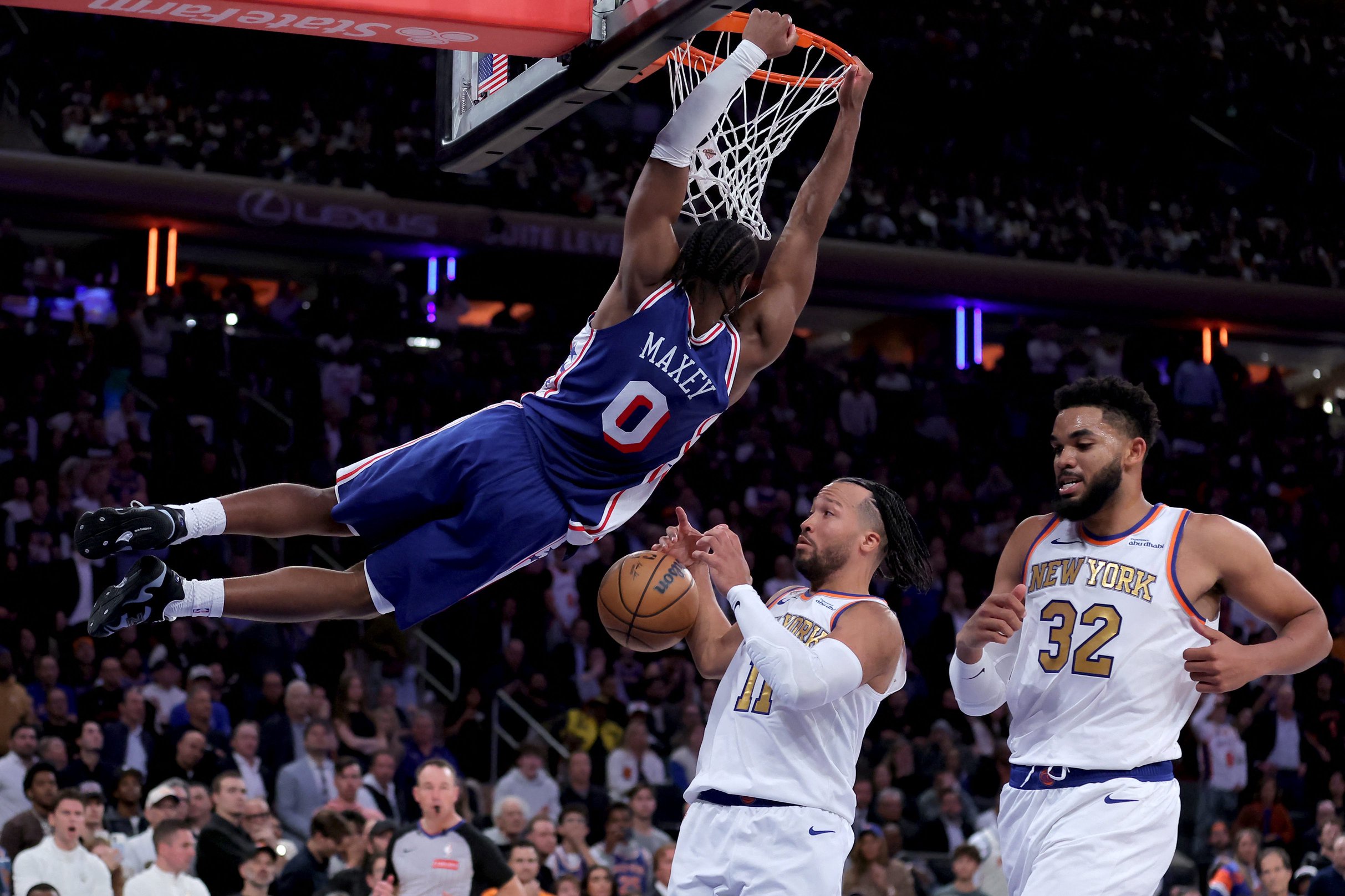 Oct 20, 2026; New York, New York, USA; Philadelphia 76ers guard Tyrese Maxey (0) hangs on the rim after a dunk against New York Knicks guard Jalen Brunson (11) and center Karl-Anthony Towns (32) during the fourth quarter at Madison Square Garden. Mandatory Credit: Brad Penner-Imagn Images