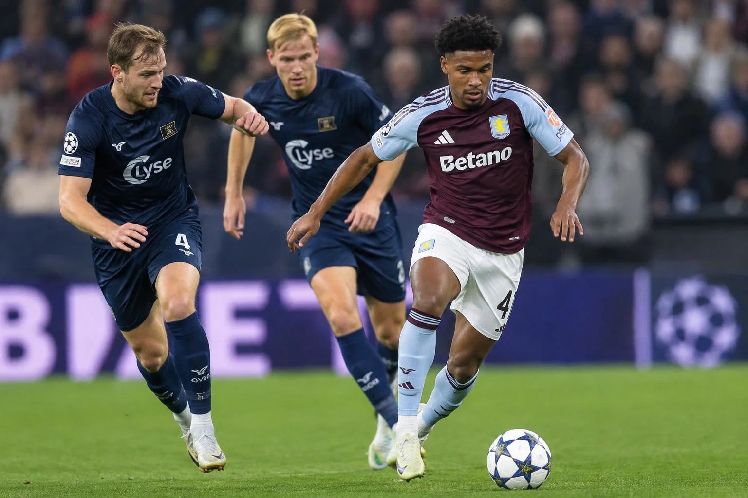 Aston Villa's Alysson Edward dribbling the ball while two Viking Stavanger FK defenders are trying to chase and tackle him fr