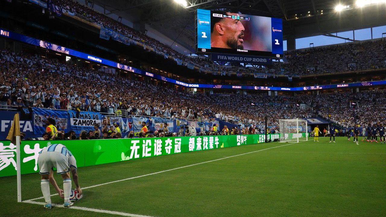 Lionel Messi bends down to place the ball during the World Cup match between Argentina and Cape Verde. Other players gather in the box. 