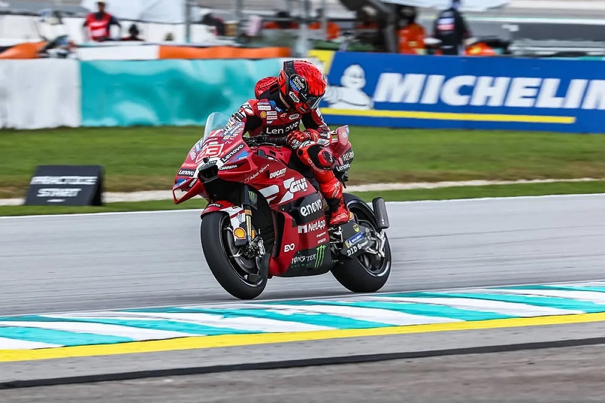 Rider in red Ducati leathers on a red MotoGP bike leaning through a corner at Sepang, Malaysian Grand Prix practice