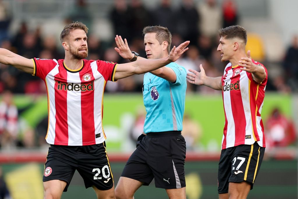 Referee John Brooks gestures as Kristoffer Ajer and Vitaly Janelt of Brentford react.