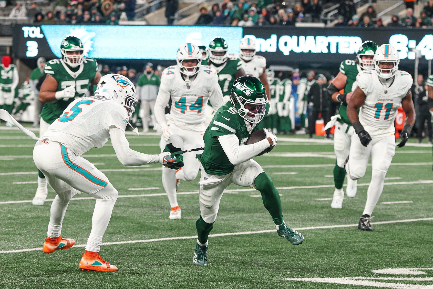 Jan 5, 2025; East Rutherford, New Jersey, USA; New York Jets wide receiver Garrett Wilson (5) breaks a tackle by Miami Dolphins cornerback Jalen Ramsey (5) during the first half at MetLife Stadium. Mandatory Credit: Vincent Carchietta-Imagn Images