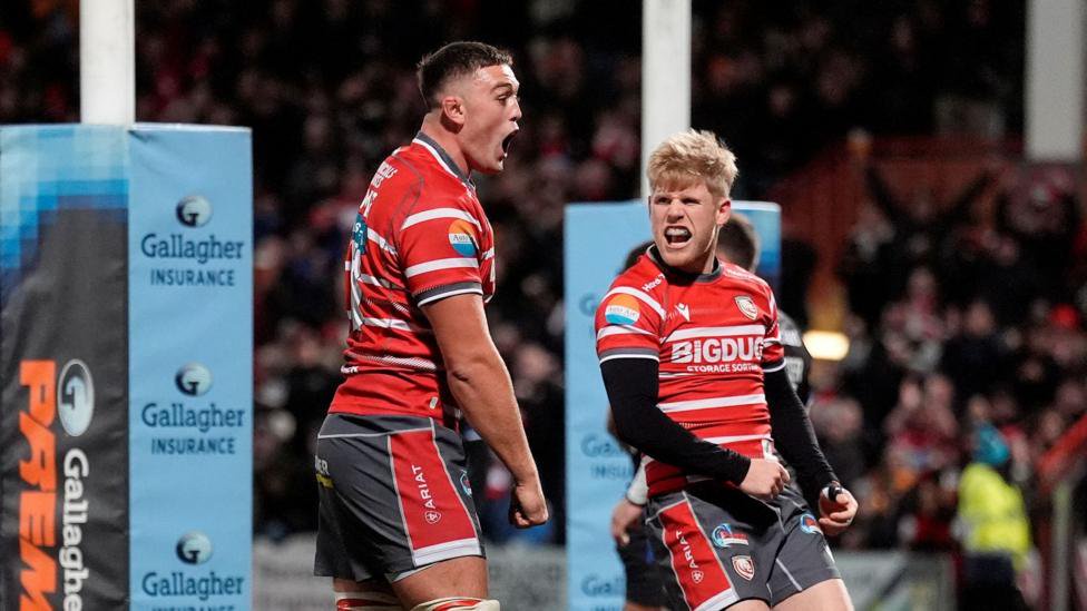 Freddie Thomas (left) stands with his fists held low and clenched and George Barton (right) looks to his right at Thomas as the two celebrate a try