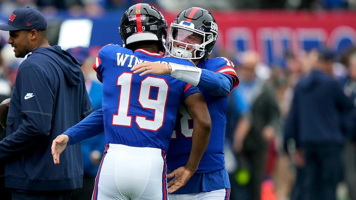 Jameis Winston receives a hug from J.J. McCarthy before an NFL game.