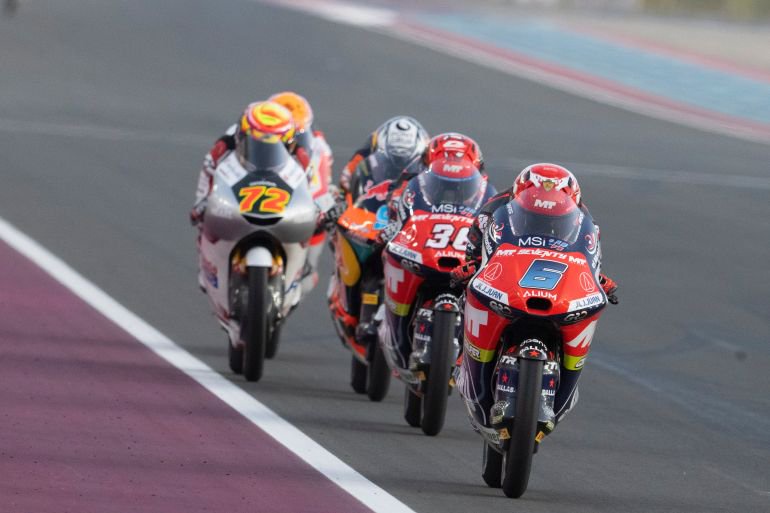 A group of motorcyclists race on a track.