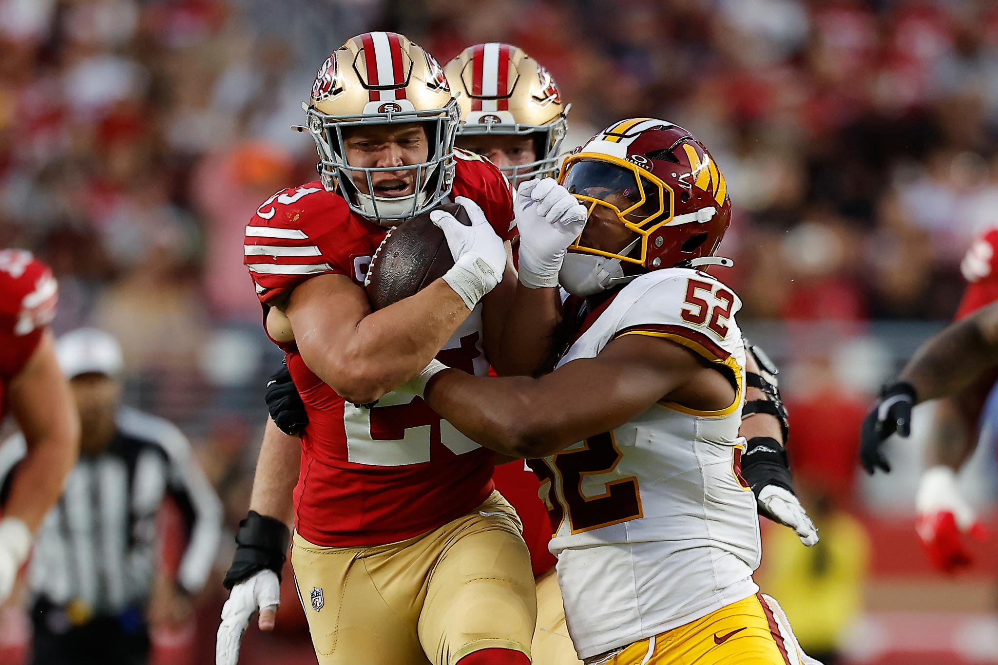 Christian McCaffrey running with the football while being tackled by an opponent.