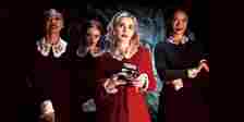 Sabrina Spellman takes a picture alongside the Weird Sisters in Chilling Adventures of Sabrina.