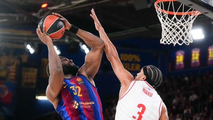 Basketball player in blue jersey attempts a shot while being blocked by a defender in white jersey during a EuroLeague game.