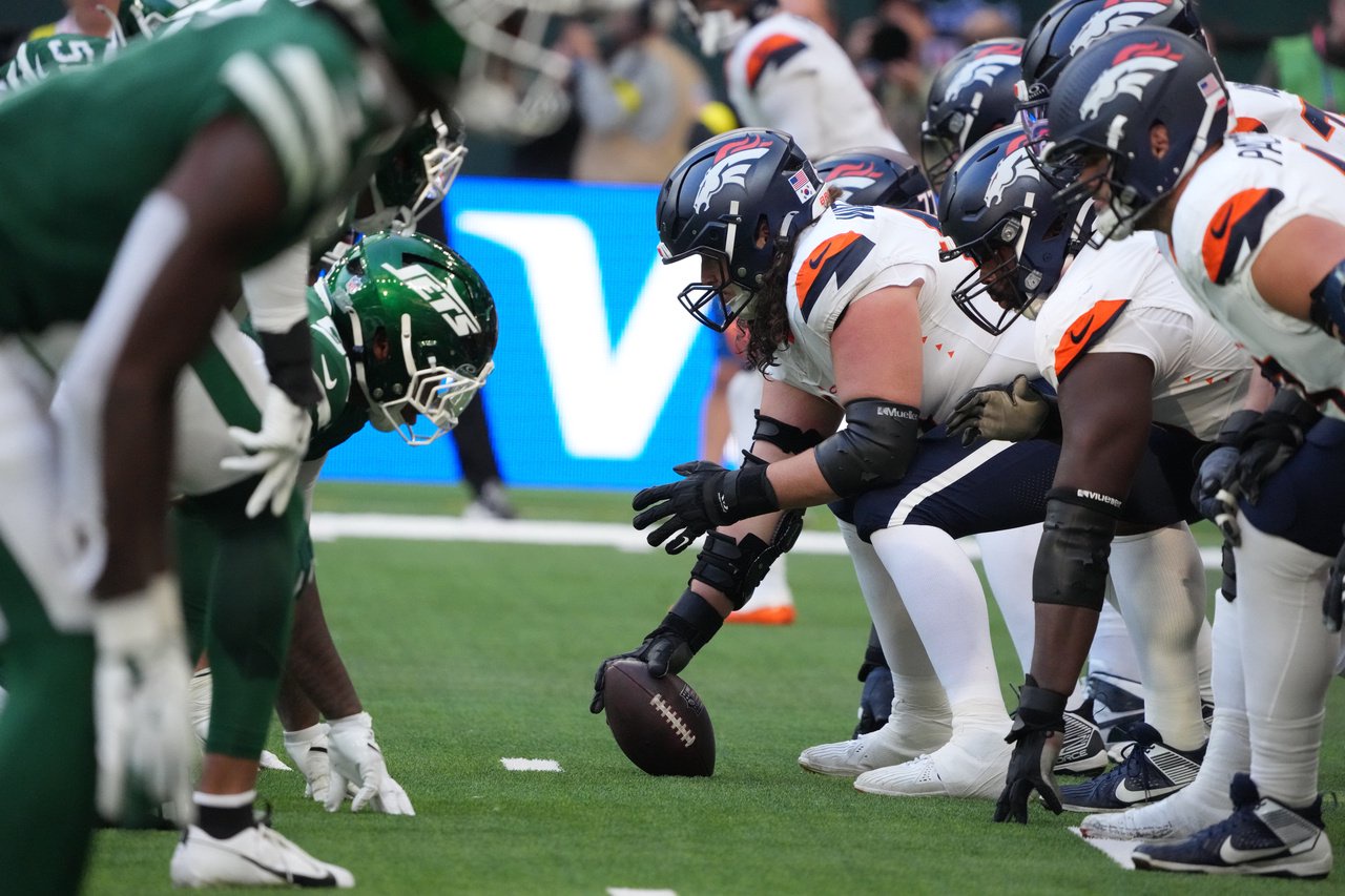 Helmets at the line of scrimmage as Denver Broncos center Luke Wattenberg (60) snaps the ball against the New York Jets during an NFL International Series game at Tottenham Hotspur Stadium. Mandatory Credit: Kirby Lee-Imagn Images