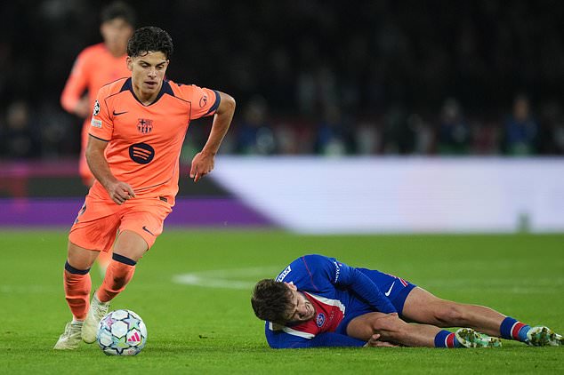 PSG's Khvicha Kvaratskhelia grimaces in pain after a challenges for the ball with Barcelona's Xavi Espart, left, during the Champions League opening phase soccer match between Paris Saint-Germain and FC Barcelona in Paris, Tuesday, Oct. 20, 2026. (AP Photo/Thibault Camus)