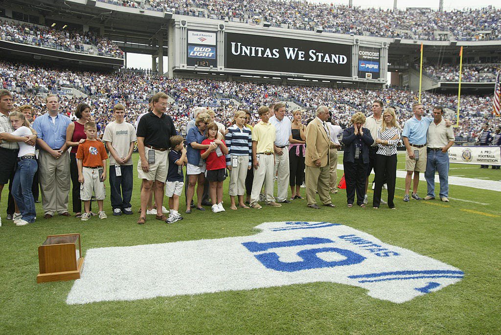 Family and friends pay tribute to Johnny Unitas as they stand behind a jersey painted with his name and uniform number on the grass prior to the game between the Tampa Bay Buccaneers and the Baltimore Ravens on Sept. 15, 2002 at Ravens Stadium in Baltimore. Unitas was one of the NFL's biggest stars during the pre-merger era when there were only two conferences and one championship game. 