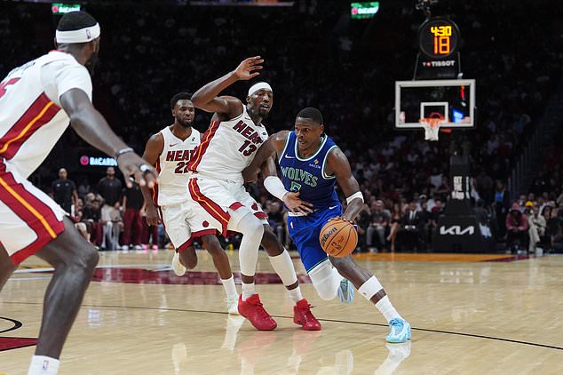 Minnesota Timberwolves guard Anthony Edwards (5) drives past Miami Heat center Bam Adebayo (13) as forward Andrew Wiggins (22) looks on during the second half of an NBA basketball game, Wednesday, Oct. 21, 2026, in Miami. (AP Photo/Rebecca Blackwell)