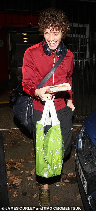 Casual: Bobby cut a sporty figure in black tracksuit bottoms and a red jacket, which he styled with olive slip-on trainers