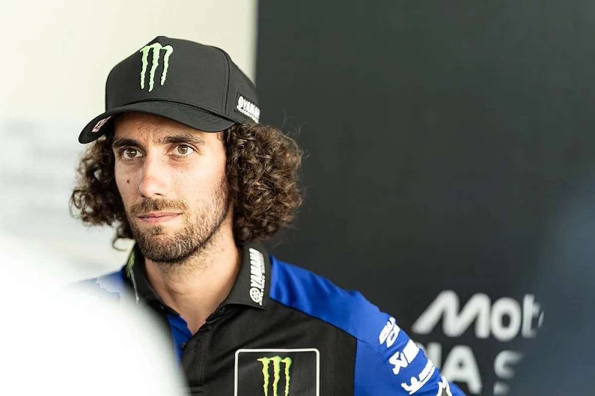 A rider in a black Monster Energy cap and blue-and-black Yamaha team shirt speaks in the MotoGP paddock, Rins-related Qatar GP story.