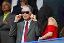 John W Henry, Owner of Liverpool, plugs his ears as he adjusts his ear defenders (obscured) as he stands with his family in the stand prior to the ...