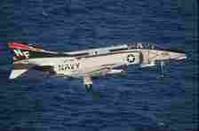 A US Navy F-4 Phantom II flying close to the ocean.