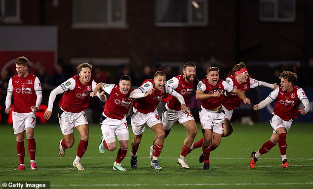 Fleetwood Town players celebrate after Jay Lynch saves a penalty from Bruno Guimaraes of Arsenal to win the match