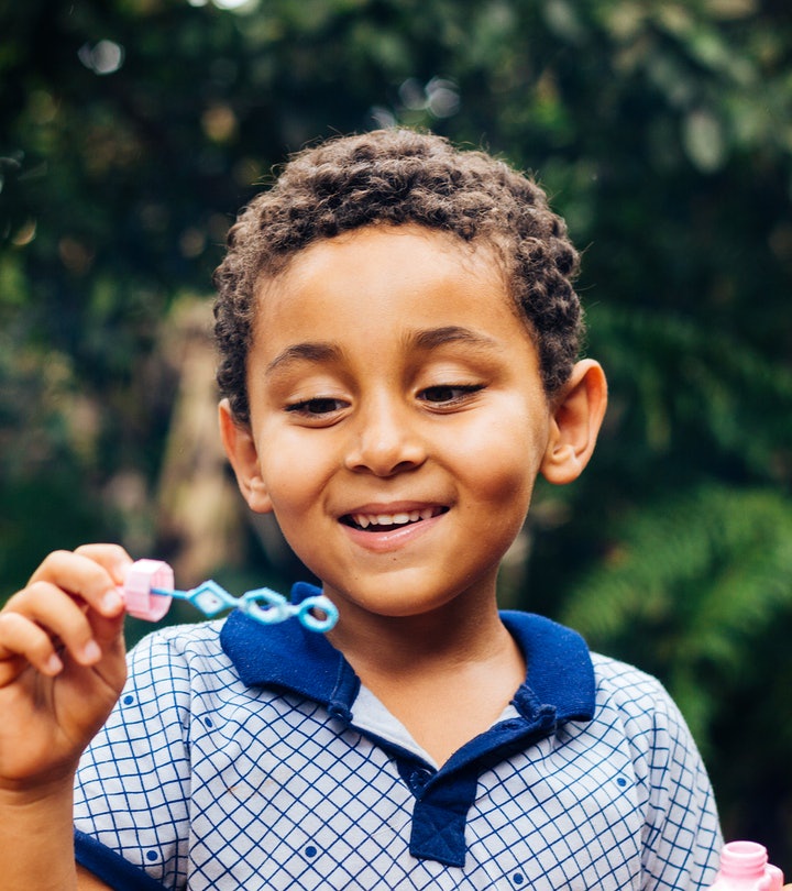 
Smiling Brazilian child playing with soap bubbles in the home garden. Boy happy. Lifestyle. Childre...