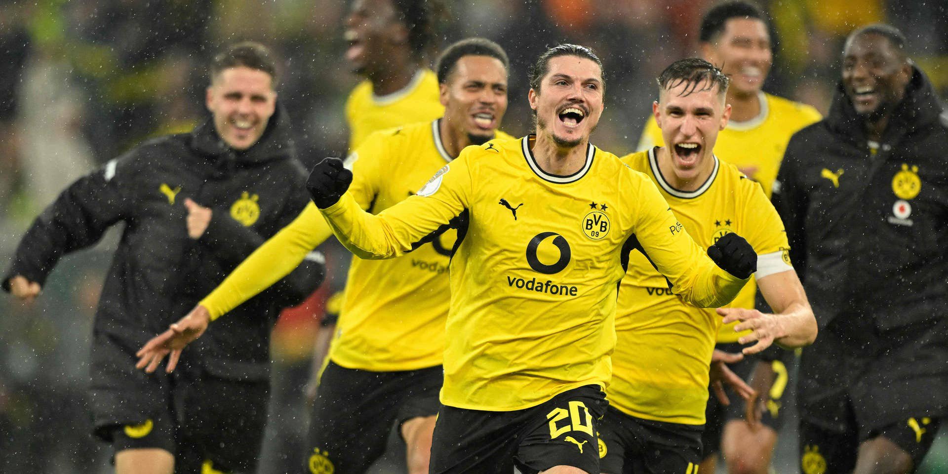 Borussia Dortmund-Spieler jubeln im Regen nach einem Torerfolg im DFB-Pokalspiel.