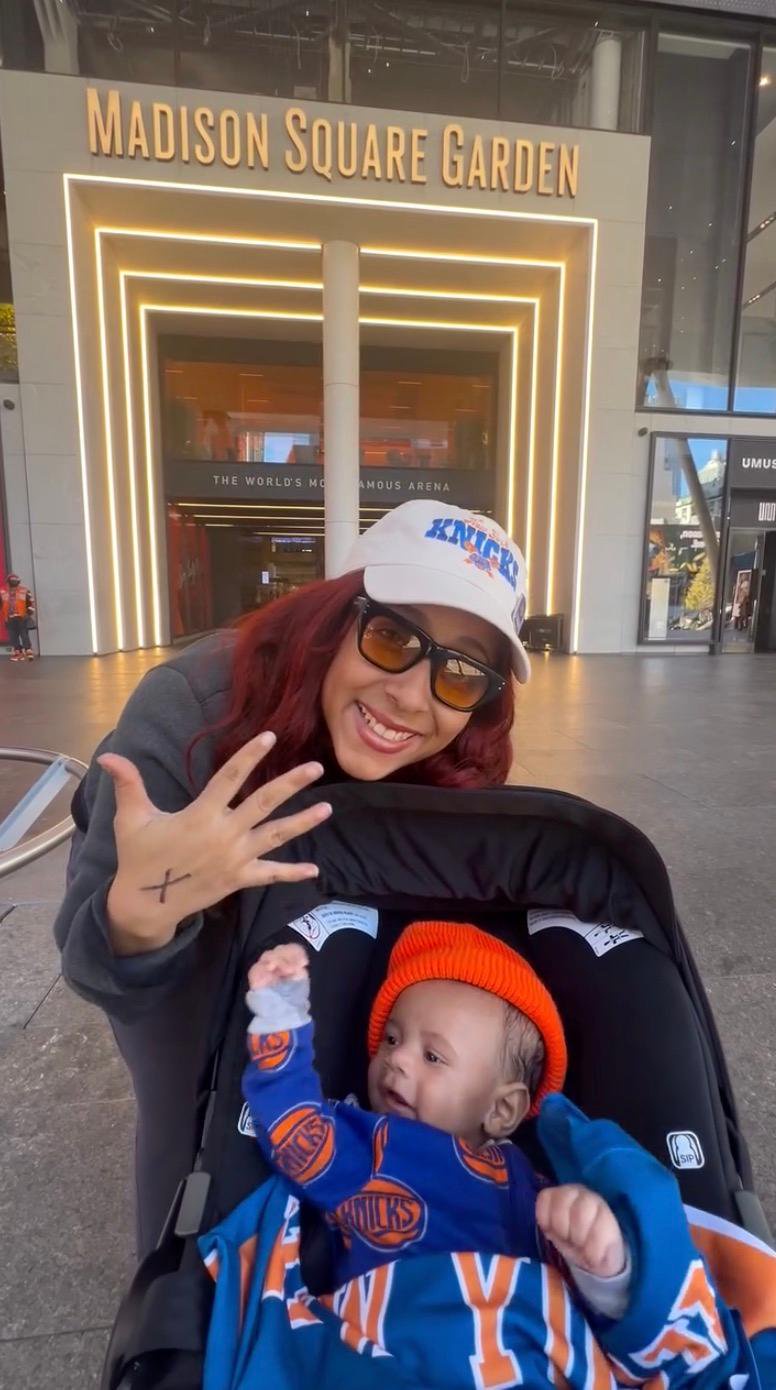 A woman holding her newborn son in a stroller outside Madison Square Garden.