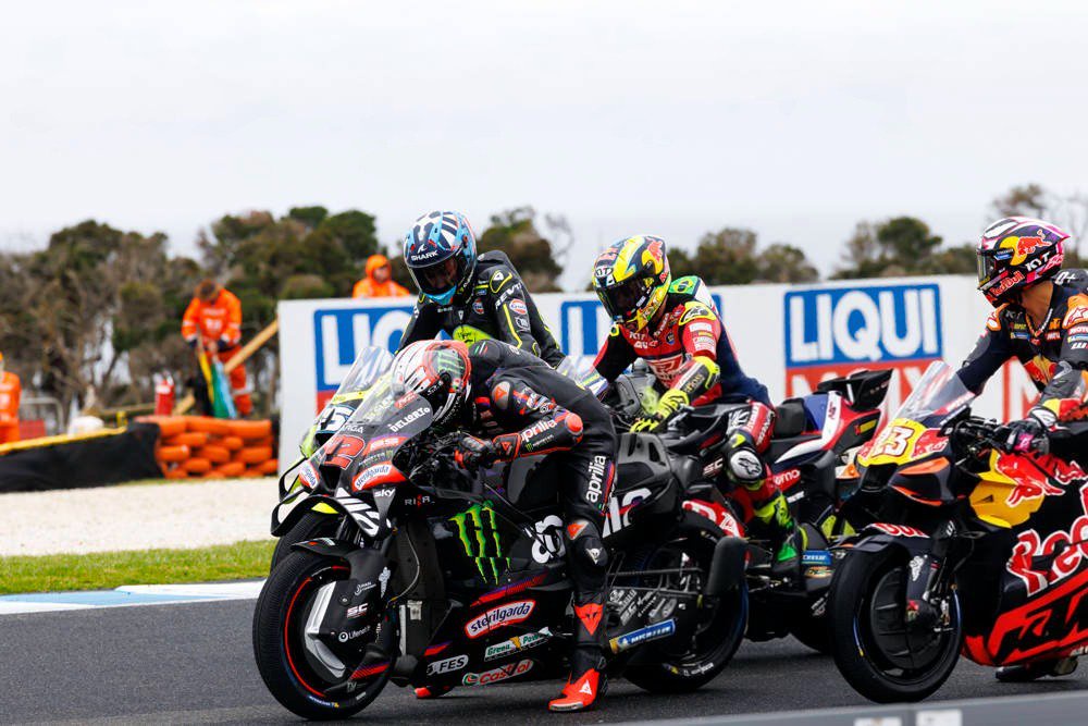 Marco Bezzecchi on his Aprilia in a Monster-branded race suit leading a MotoGP grid at Phillip Island, with rivals behind him