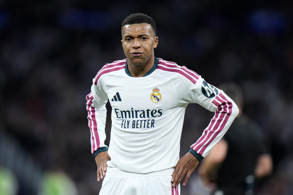 Rodrygo Goes in Real Madrid white and maroon kit, hands on hips, on the pitch.