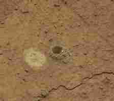 There are more than 40 holes on Mars. The drill aboard the Curiosity rover created the hole in a rock investigators call Mammoth Lakes. The bright spot to the left of the hole is where the rover smoothed a small area to collect spectroscopic data. Credit: NASA/JPL-Caltech/MSSS