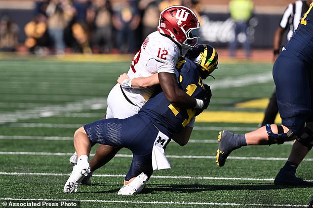Michigan quarterback Tommy Carr (14) gets sacked by Indiana defensive end Tobi Osunsanmi (12) in the fourth quarter of an NCAA college football game Saturday, Oct. 24, 2026, in Ann Arbor, Mich. (AP Photo/Lon Horwedel)