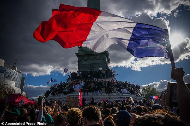 A person holds a French national flag during a protest against under-resourced schools in Paris, Thursday, Oct. 8, 2026. (AP Photo/Aurelien Morissard)