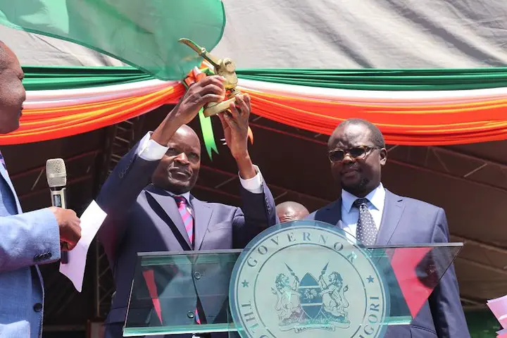 Migori outgoing governor Okoth Obado (carrying the county seal) while incoming governor Ochillo Ayacko looks on