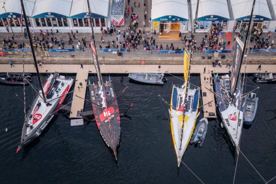 This aerial photograph taken on October 28, 2026 shows monohull Imoca class moored in the harbour of Saint-Malo northwestern France, at sunset, a few days prior to the start of the Route du Rhum solo sailing race from Saint-Malo, to Pointe-a-Pitre in the French overseas island of Guadeloupe. (Photo by Lou BENOIST / AFP) - SAILING-FRA-RHUM