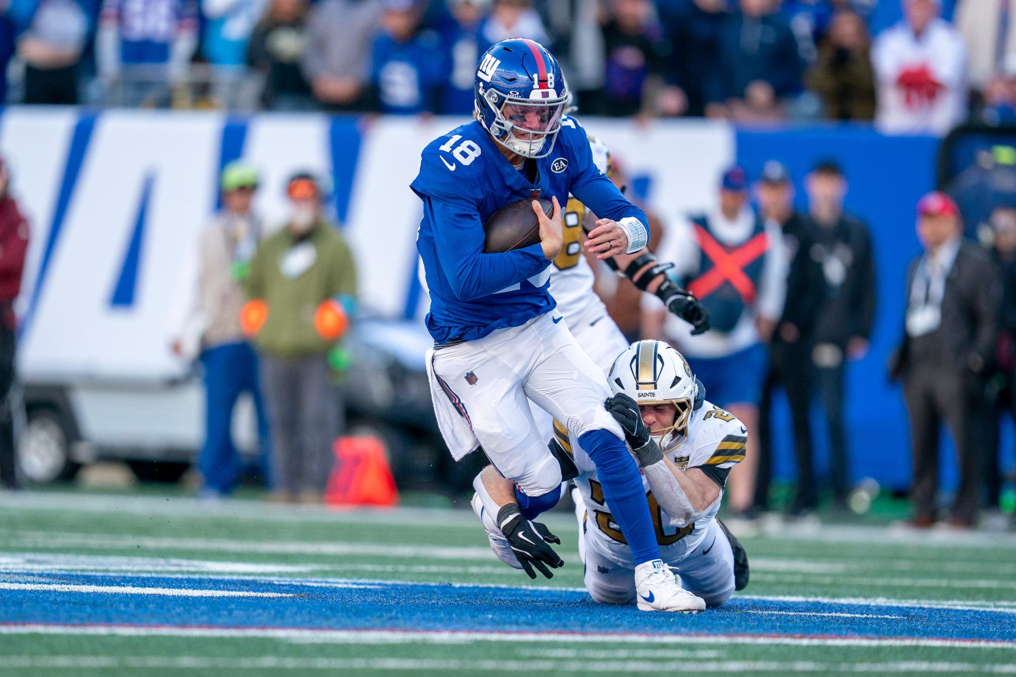 New York Giants quarterback J.J. McCarthy (18) runs with the ball while being tackled during a game against the New Orleans Saints.