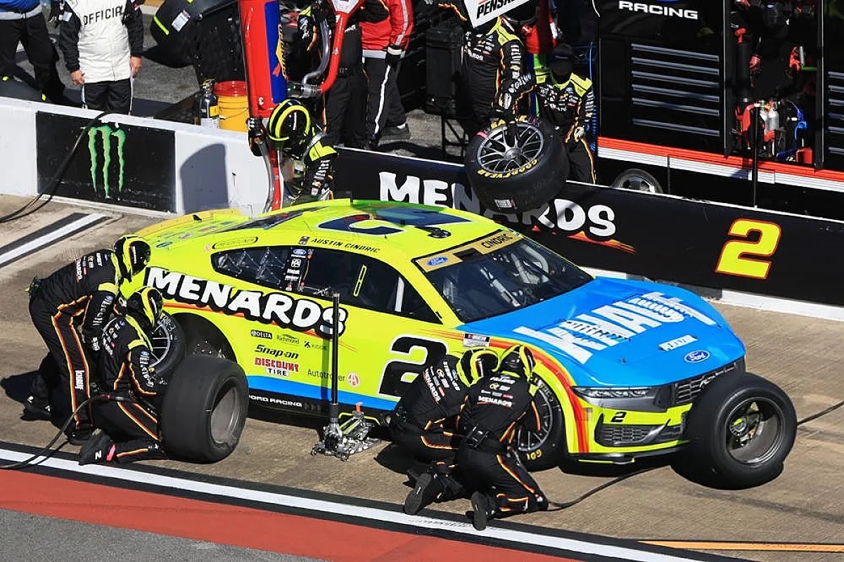 Austin Cindric's No. 2 Menards Ford NASCAR car during a pit stop, crew changing tires at the track.