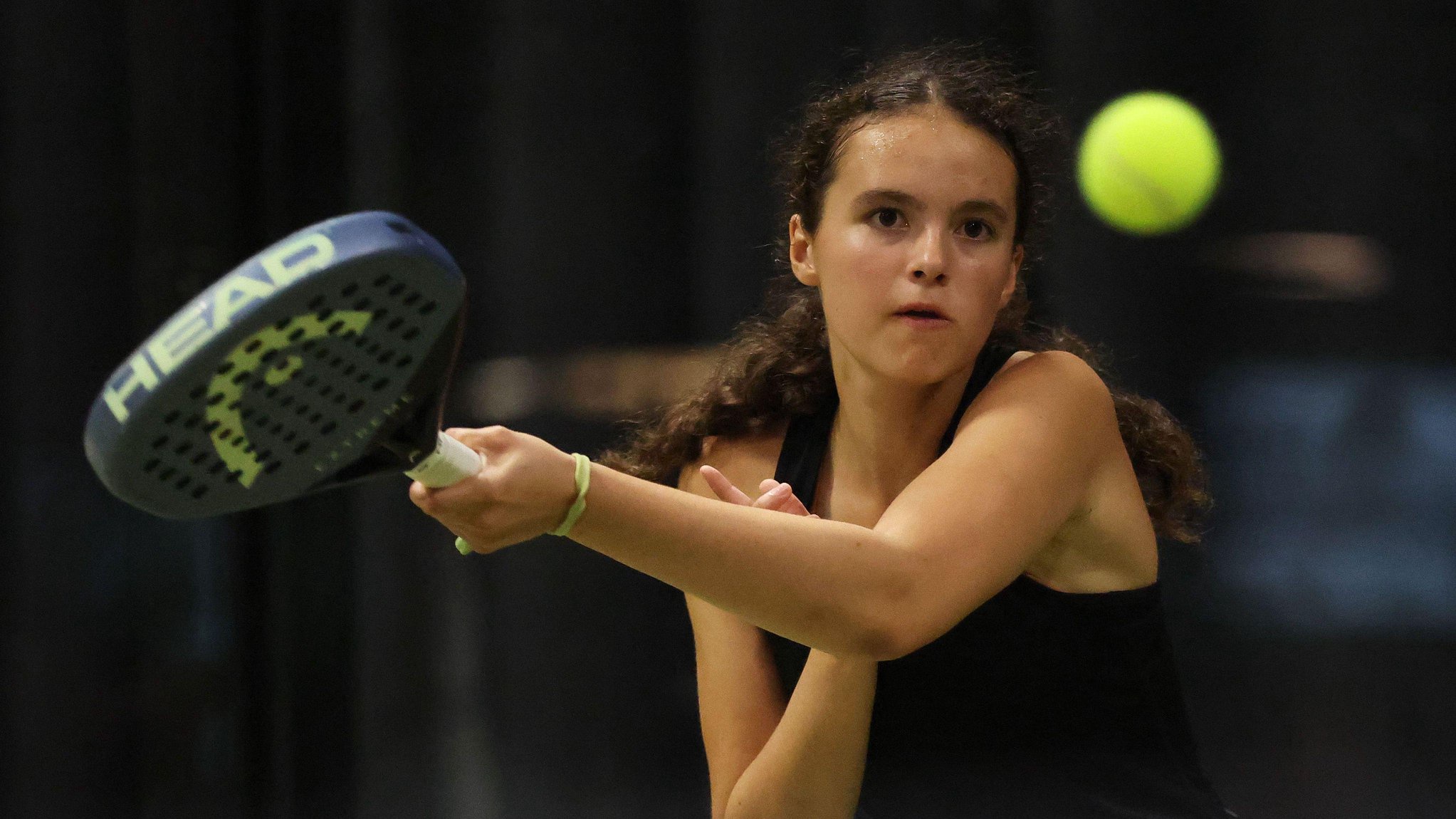 Chloe De La Mare watches the ball after swinging her padel racket during a match