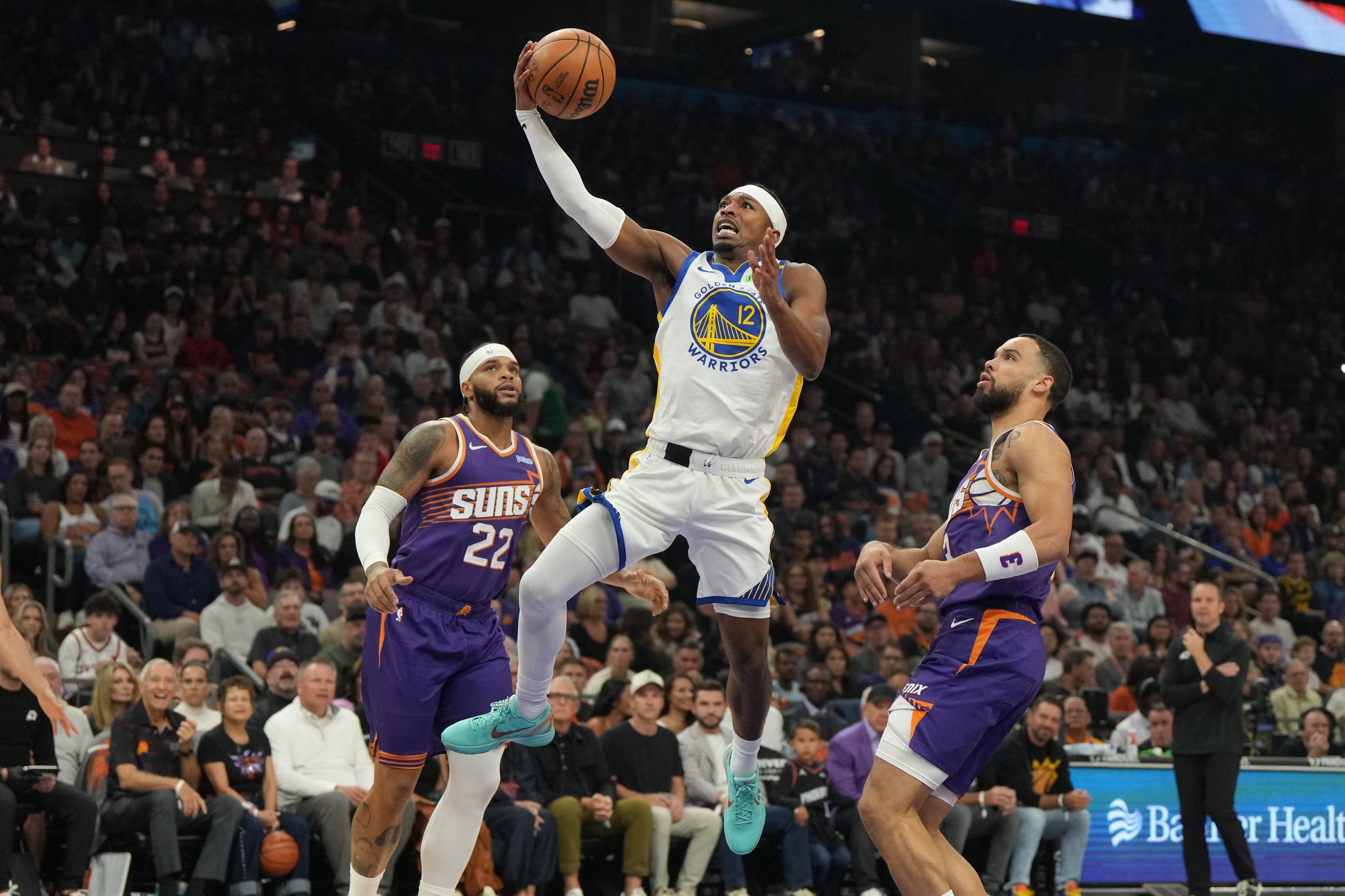 Oct 24, 2026; Phoenix, Arizona, USA;  Golden State Warriors guard Brandon Williams (12) drives between Phoenix Suns forward Miles Bridges (22) and forward Dillon Brooks (3) in the first half at Mortgage Matchup Center.  Mandatory Credit: Rick Scuteri-Imagn Images