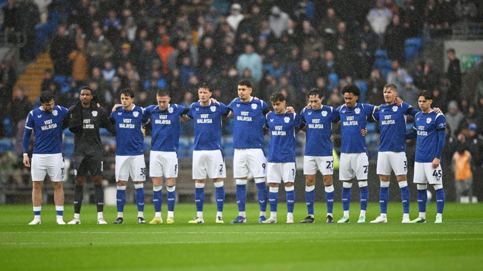 Cardiff City players link arms as they observe a minute's silence