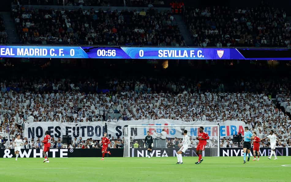 Torcedores do Real Madrid exibem uma faixa com os dizeres "Isto não é futebol, isto é Tebas e Negreira", em referência a um caso de corrupção envolvendo supostos pagamentos de suborno ao ex-chefe de arbitragem, durante a partida do Campeonato Espanhol entre Real Madrid CF e Sevilla FC, no estádio Santiago Bernabéu, em Madri, em 18 de outubro de 2026. (Foto: Oscar Del Pozo / AFP) Torcedores do Real Madrid exibem uma faixa com os dizeres "Isto não é futebol, isto é Tebas e Negreira", em referência a um caso de corrupção envolvendo supostos pagamentos de suborno ao ex-chefe de arbitragem, durante a partida do Campeonato Espanhol entre Real Madrid CF e Sevilla FC, no estádio Santiago Bernabéu, em Madri, em 18 de outubro de 2026. (Foto: Oscar Del Pozo / AFP)
