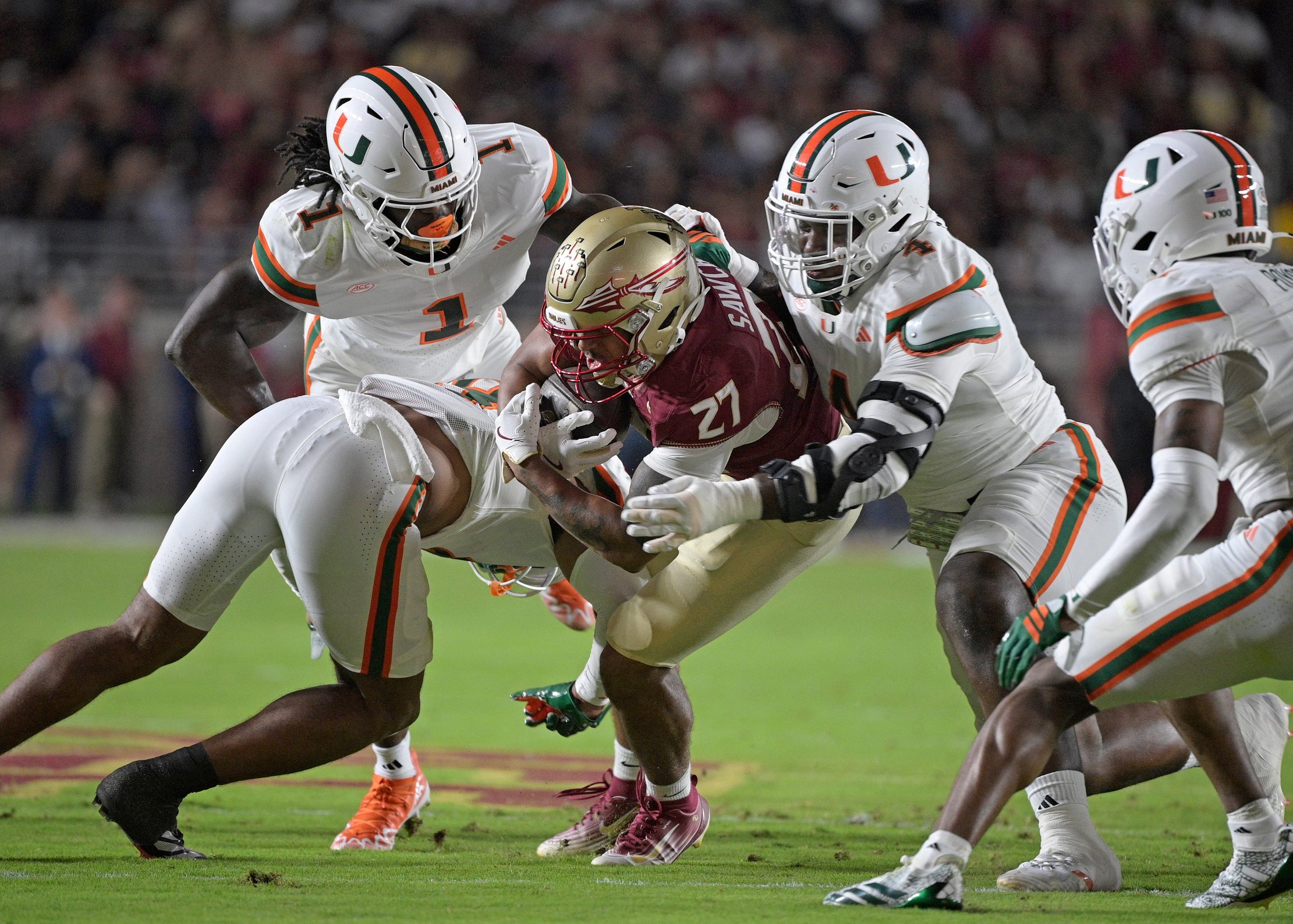 Oct 4, 2025; Tallahassee, Florida, USA; Miami Hurricanes defensive lineman Rueben Bain Jr. (4) tackles Florida State Seminoles running back Gavin Sawchuk (27) during the first half at Doak S. Campbell Stadium. Mandatory Credit: Melina Myers-Imagn Images