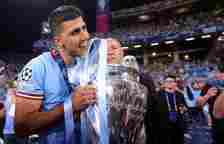 Rodri bites the Champions League trophy.