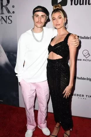Justin Bieber and Hailey Bieber attend the premiere of YouTube Originals' "Justin Bieber: Seasons". He's wearing a white top and pink trousers while she's wearing a sequin black dress
