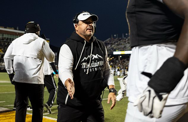 Appalachian State head coach Dowell Loggains, center, greets his players as they return to the bench during the first half of an NCAA college football game against James Madison in Boone, N.C., Thursday, Oct. 22, 2026. (Daniel Lin/Daily News-Record Via AP)