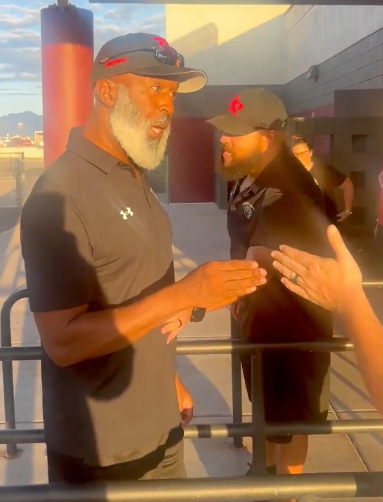 Lovie Smith and Head Coach Miles Smith reacting to parents at an athletic facility.