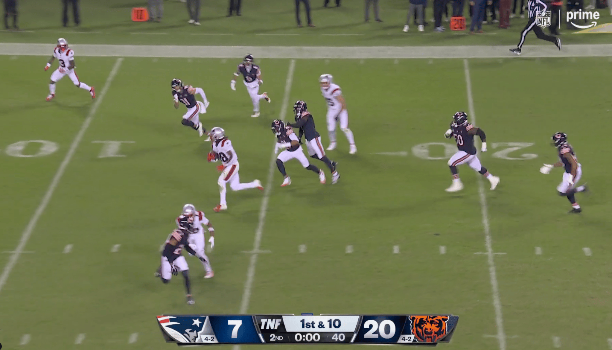 Football players in action on the field with the score shown on the screen.