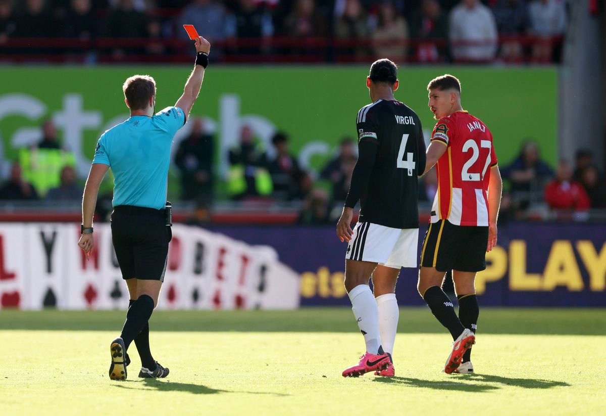 Referee John Brooks shows a red card to Yehor Yarmolyuk of Brentford  as Virgil van Dijk of Liverpool and Vitaly Janelt of Brentford look on. 
