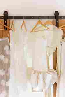 Bride and Bridesmaids White Wedding Outfits Hanging on Coat Hangers 