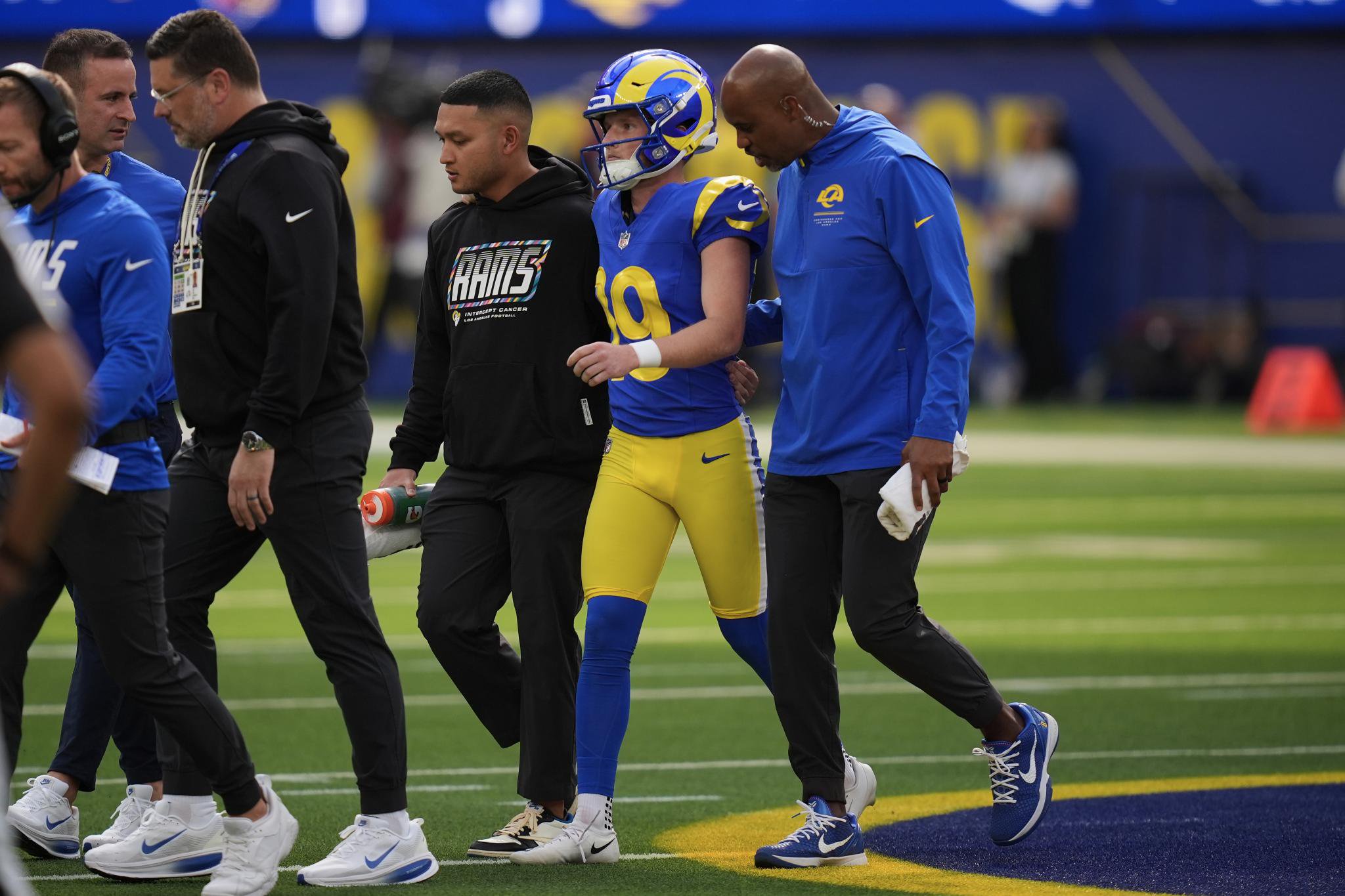 Los Angeles Rams kicker Blake Grupe (19) walks off the field with trainers during a game.