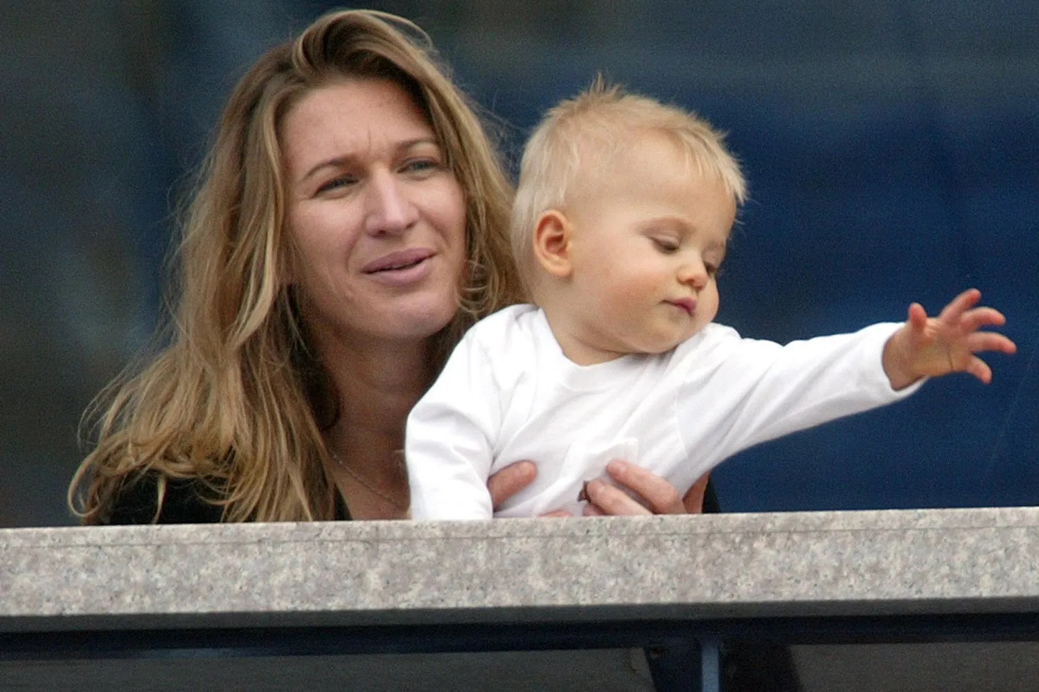 Steffi Graf and her son Jaden Gil watch as Andre Aggasi plays against Ramon Delgado of Paraguay at the 2002 US Open Tennis Tournament 31 August, 2002 in Flushing Meadows, NY. 