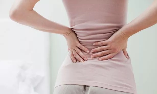 A photo of a woman holding her lower back